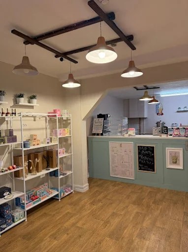 Inside Honey & Pearls: white shelves of gifts, a mint-green counter and pendant lights