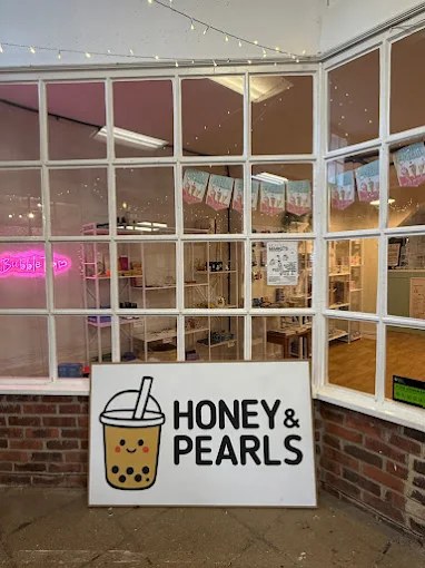 The Honey & Pearls shopfront in the Folly Market, with the cup logo sign and a pink neon Bubble Tea light